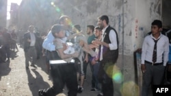 Un homme porte un enfant blessé après quatre roquettes tirées depuis la Syrie dans la ville méridionale turque de Kilis, tuant quatre Syriens - dont trois enfants, le 18 avril 2016. (AFP PHOTO)