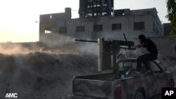 Foto dari Aleppo Media Center (AMC) ini menunjukkan gambar seorang pemberontak Suriah tengah menembakkan senjatanya ke arah pasukan pemerintah yang setia kepada Presiden Bashar Assad di Aleppo (9/11).