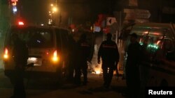 Police vehicles stop in front of burning tires set up by protesters during demonstrations against rising prices and tax increases, in Tunis, Tunisia, Jan. 9, 2018.