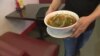 Pho is served in a large white bowl, with light rice noodles, beef -- which has been cooled so it can be sliced very thin -- and vegetables.