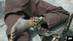 FILE - A patient at a home for the mentally ill is chained to a table in Monrovia, Liberia, Aug. 29, 2003.