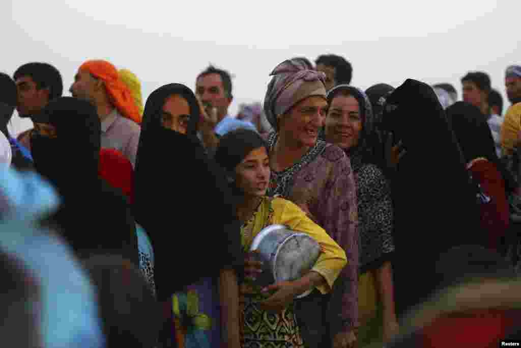 Iraqi refugees who fled from the violence in Mosul line up to receive free food during the holy fasting month of Ramadan, inside the Khazer refugee camp on the outskirts of Irbil, Iraq, June 29, 2014.
