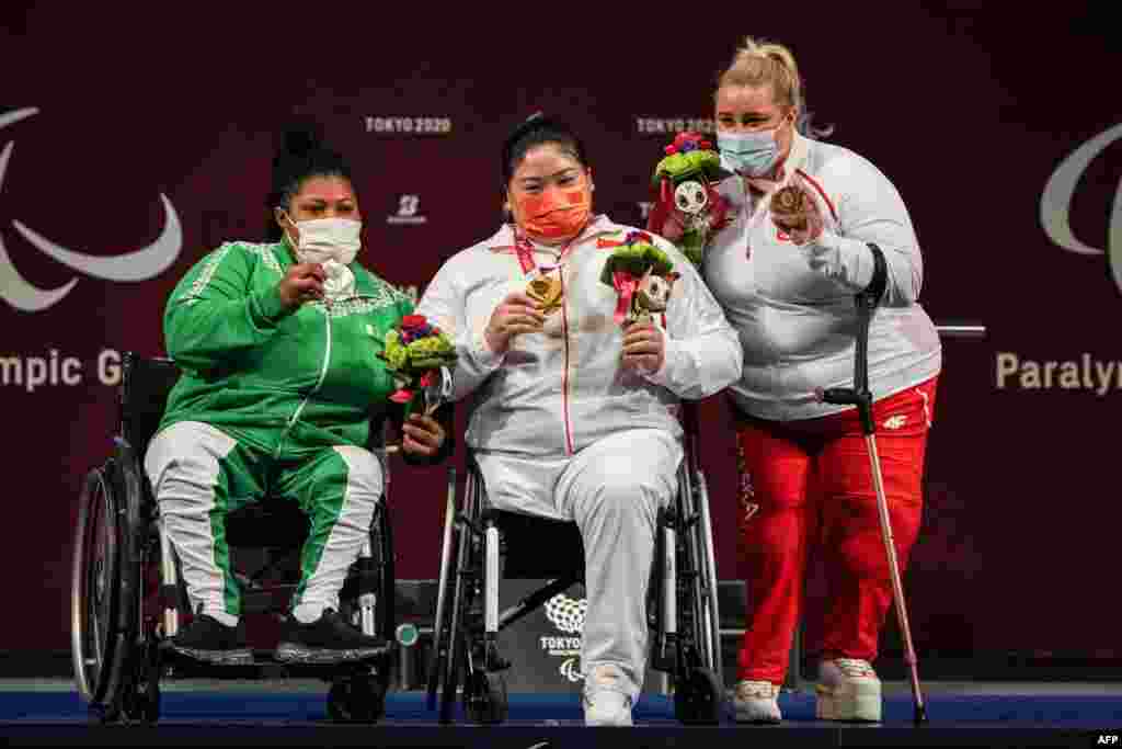 China's Xuemei Deng (C, gold), Nigeria's Loveline Obiji (L, silver) and Poland's Marzena Zieba (bronze) pose for photographers during the victory ceremony of powerlifting women's +86kg of the Tokyo 2020 Paralympic Games at Tokyo International Forum in Tokyo, Japan. (Photo by Yasuyoshi CHIBA / AFP)