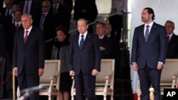 Lebanese President Michel Aoun, center, Lebanese Prime Minister Saad Hariri, right, and Lebanese Parliament Speaker Nabih Berri, left, attend a military parade to mark the 74th anniversary of Lebanon's independence from France in downtown Beirut, Nov. 22, 2017.