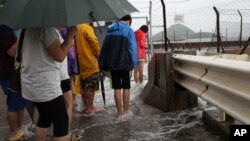 People play with overflown water caused by Typhoon Nida in Hong Kong, Tuesday, Aug. 2, 2016.