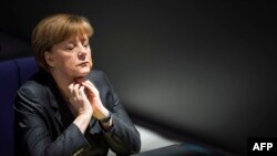 German Chancellor Angela Merkel listens to Gregor Gyisi of the Left party answer her speech on the government's policy on Ukraine at the Bundestag, Germany's lower house of parliament in Berlin on March 13, 2014.
