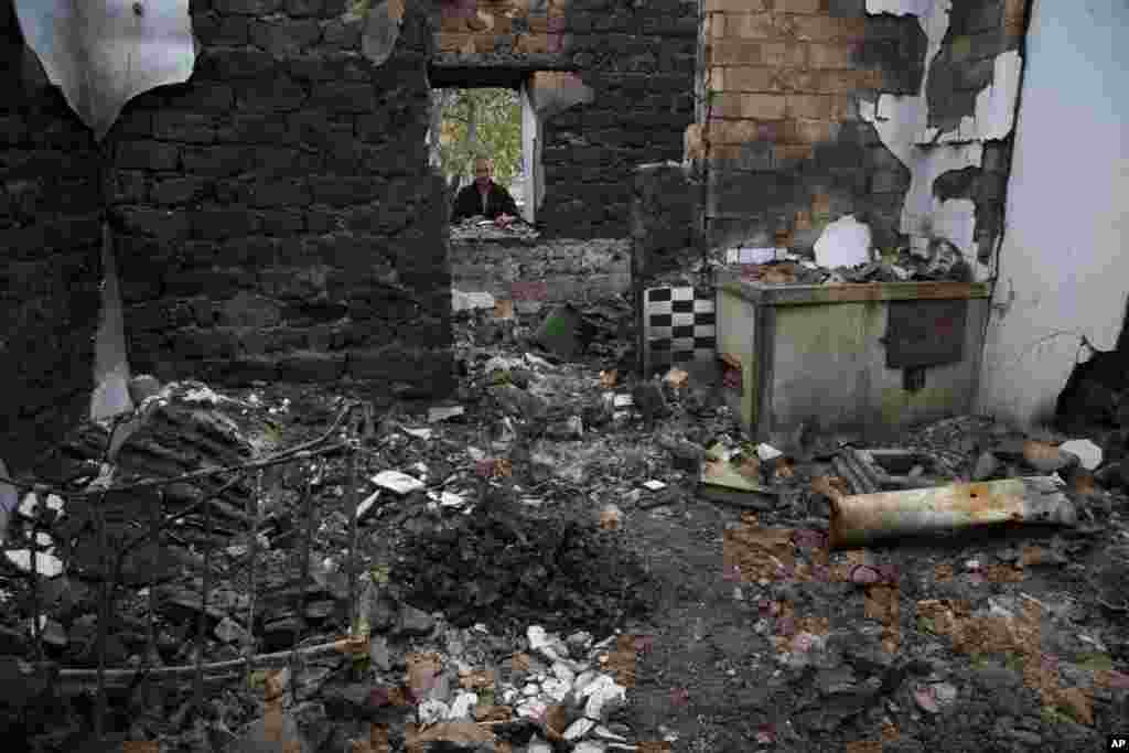 Vitaly, surname not given, looks into his destroyed house outside of the town of Illovaysk, eastern Ukraine, Oct. 16, 2014.