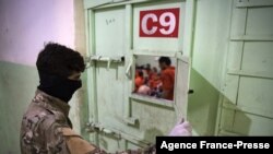 Seorang anggotaPasukan Demokratik Suriah (SDF) berdiri menjaga sel tahanan di mana sejumlah pria yang diduga menjadi anggota ISIS ditahan dalam sel tersebut yang berada di wilayah timur laut Suriah di kota Hasakeh, pada 26 Oktober 2019. (Foto: 