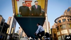 Un écran de télévision géant retransmettant la réunion du dirigeant nord-coréen Kim Jong Un et du président chinois Xi Jinping au Grand Palais du Peuple à Beijing, mardi 19 juin 2018. (AP Photo / Andy Wong)