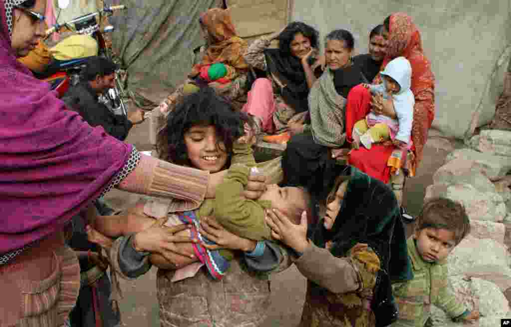 Seorang petugas kesehatan Pakistan memberikan vaksin polio kepada anak-anak di permukiman miskin di kota Lahore.