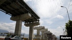 FILE - Commuters drive past a construction site by Odebrecht of the Caracas-Guatire metro rail project in Guatire, Venezuela, March 28, 2017.