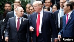 U.S. President Donald Trump and Russia's President Vladimir Putin talk as Vietnam's President Tran Dai Quang, right, looks on, during the photo session at the APEC Summit in Danang, Vietnam, Nov. 11, 2017.
