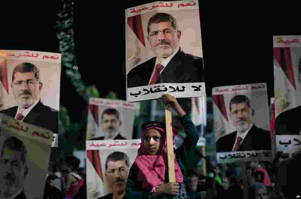 Supporters of Egypt's ousted President Mohamed Morsi carry posters with Arabic writing which reads "Yes for legality, No for the coup" during a protest outside Rabaah al-Adawiya mosque, Cairo, August 6, 2013.