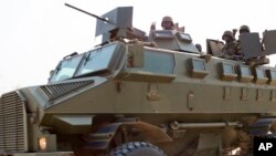 FILE - Soldiers from the Uganda People's Defense Force (UPDF) are seen driving in an armored vehicle through the streets of Bor, Jonglei State, South Sudan, Jan. 19, 2014.