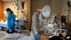 FILE - Dr. Rafik Abdou checks on a COVID-19 patient at Providence Holy Cross Medical Center in the Mission Hills section of Los Angeles.