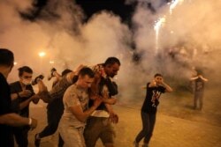 FILE - Protesters carry a man wounded during clashes with police after the presidential election in Minsk, Belarus, Aug. 10.