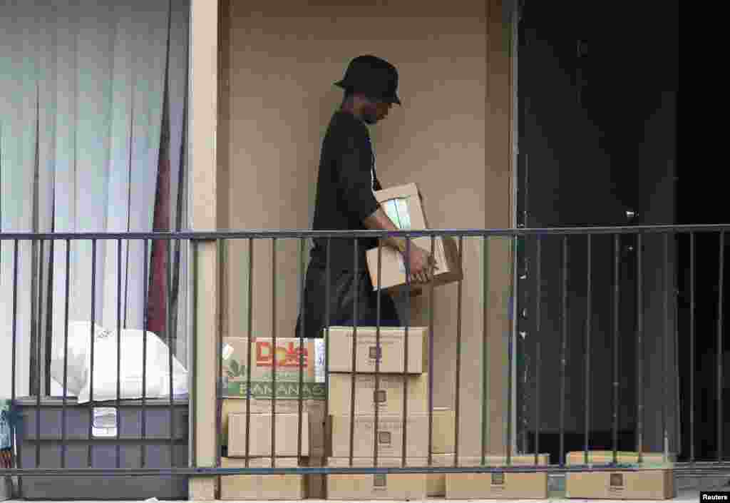 Un homme sort de la résidence de la famille mise en quarantaine pour récupérer les cartons de produits alimentaires que la Croix Rouge a déposés devant l’appartement où habitait le malade atteint d’Ebola, à Dallas, le 2 octobre 3014.