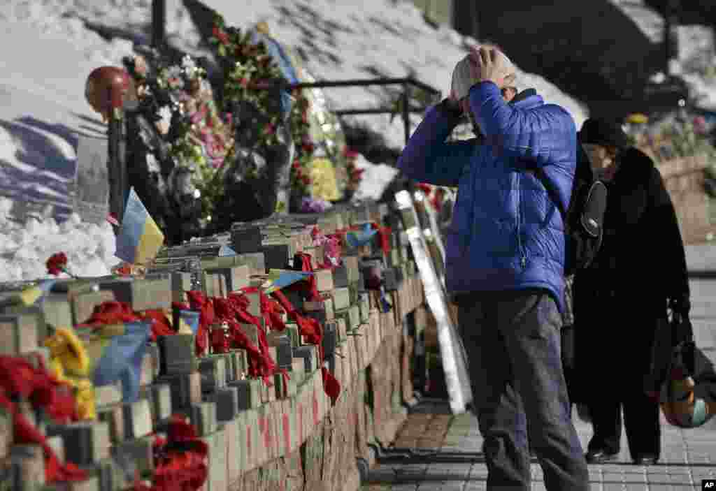 A man looks at pictures of victims of the Maidan Square protests, which happened nearly one year ago, from February 20-22, placed as a commemoration in Kyiv, Ukraine, Feb. 17, 2015.