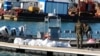 Des garde-côtes tunisiens se tiennent à côté des cadavres de migrants dans le port de Sfax, en Tunisie, le 24 décembre 2020. 