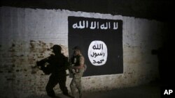 Seorang tentara Irak memeriksa terowongan kereta api yang dihiasi bendera kelompok Negara Islam, yang digunakan sebagai kamp pelatihan untuk pejuang ISIS, di Mosul barat, Irak, 1 Maret 2017. (AP/Khalid Mohammed)