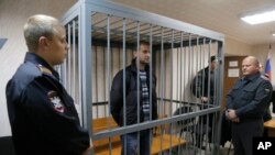 Police officers guards a cage with Greenpeace activist Ruslan Yakushev of Ukraine, Sept. 26, 2013. 