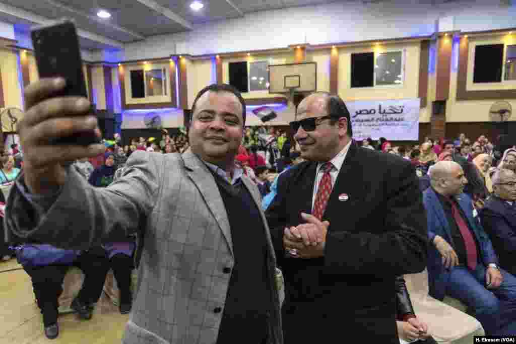 A man takes a selfie with a Sissi look-alike Tarek Gouda in Giza, March 10, 2018.