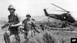 FILE - In this April 28, 1965 file photo, U.S. Marine infantry stream into a suspected Viet Cong village near Da Nang in Vietnam during the Vietnamese war. Filmmaker Ken Burns said he hopes his 10-part documentary about the War, which begins Sept. 17, 2017 on PBS, could serve as sort of a vaccine against some problems that took root during the conflict, such as a lack of civil discourse in America.