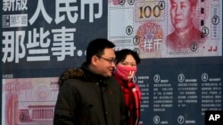 Un couple passe devant un écran montrant les caractéristiques de sécurité de la nouvelle coupure de 100 Yuan. Beijing, le lundi 11 janvier 2016 .