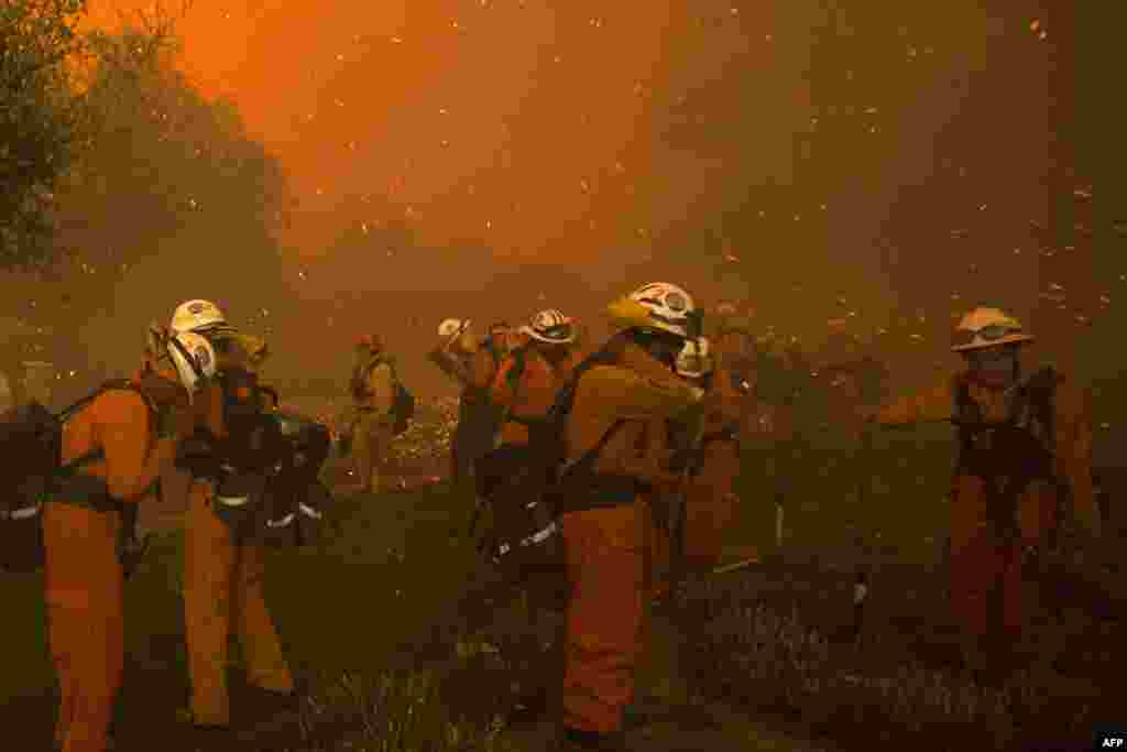 Inmate handcrew firefighters shield themselves from embers and heavy smoke as flames close in on houses at the Sand Fire near Santa Clarita, California, July 23 2016. Fueled by temperatures reaching about 108° F, the wildfire began has grown to 11,000 acres.