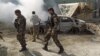 FILE - Afghan security forces walk past a burning car after a group of Taliban insurgents stormed a compound used by Afghanistan's intelligence agency in Kabul, Afghanistan, July 7, 2015.
