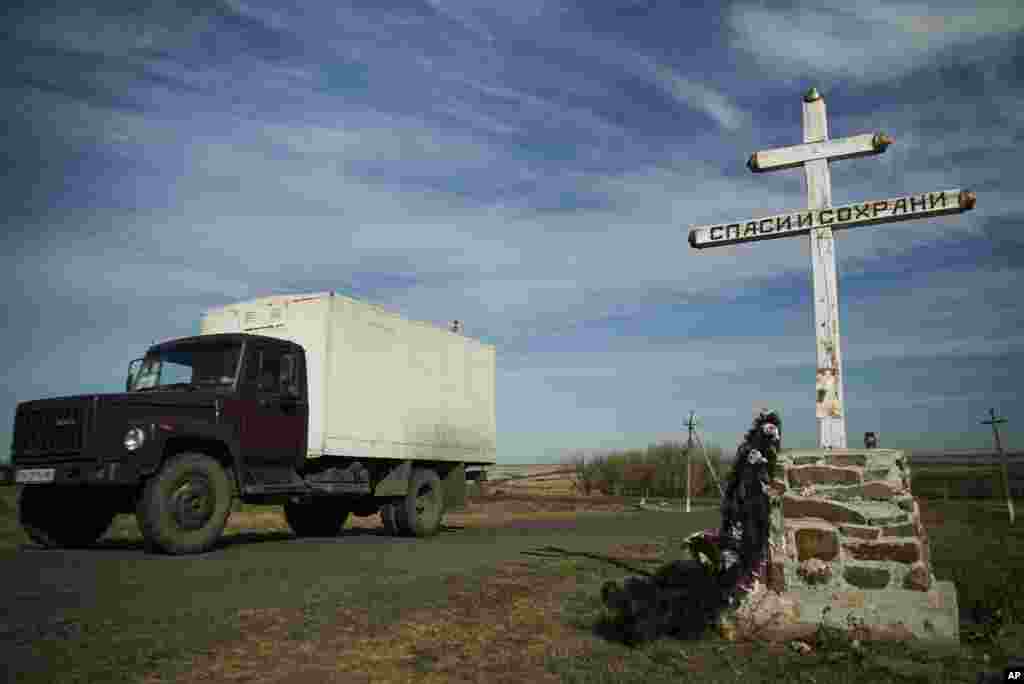 A truck drives by an Orthodox cross with a sign reading Save and Guard, at a memorial to the victims of the Malaysian Airlines MH17 plane crash, near the village of Hrabove, eastern Ukraine, October 13, 2015 .