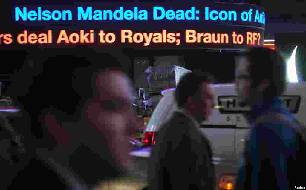 Orang melewati news ticker di Times Square yang mengumumkan wafatnya mantan Presiden Afrika Selatan Nelson Mandela, di New York, 5 Desember 2013.