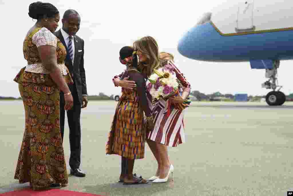 First lady Melania Trump embraces flower girl Lillian Naa Adai Sai, 8, as she receives flowers as she arrives at Kotoka International Airport in Accra, Ghana, Oct. 2, 2018.