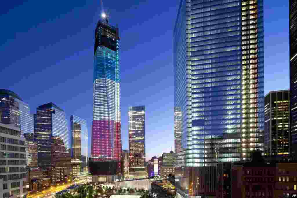 The tower known as 1 World Trade Center, left, the National September 11 Memorial, bottom left, and 4 World Trade Center, right, are bathed in light, New York, September 11, 2012.