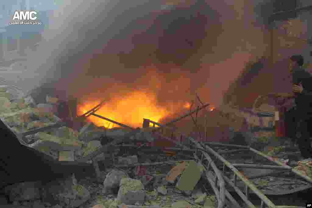 A Syrian man (right) trying to extinguishes flames of a house that was attacked by a Syrian government airstrike, Aleppo, Feb. 26, 2014.