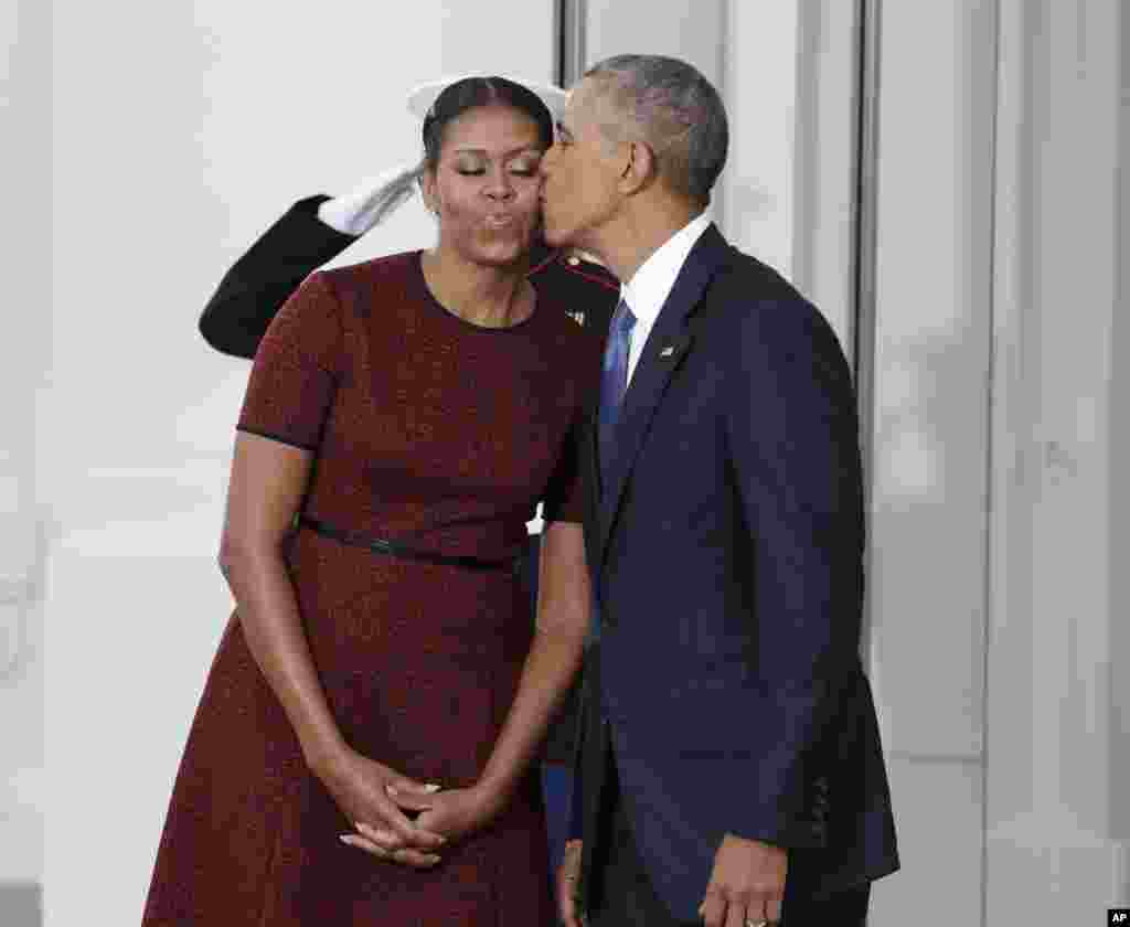President Barack Obama kisses first lady Michelle Obama as they await for the arrival of President-elect Donald Trump and his wife Melania, Jan. 20, 2017, at the White House in Washington.