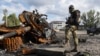Seorang tentara Ukraina berdiri di dekat tank milik pasukan Rusia yang hancur di wilayah Kharkiv, Ukraina, pada 4 Oktober 2022. (Foto: AP/Andrii Marienko)