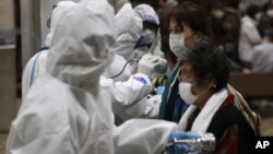 Ana auna mutanen da aka kwashe daga kusa da masana'antar nukiliya ta Fukushima domin a ga ko alamar tururi mai guba a jikinsu, talata 15 Maris 2011.