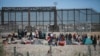 Migrants line up at the U.S. border wall after being detained by U.S. immigration authorities, seen from Ciudad Juarez, Mexico, Dec. 27, 2023. 
