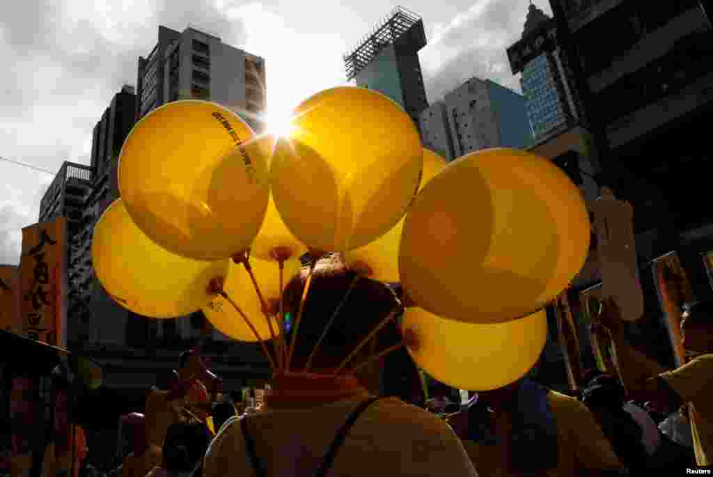 A protester carries yellow balloons featuring umbrellas, symbol of the Occupy Central movement, during a protest march on the day marking the 19th anniversary of Hong Kong&#39;s handover to Chinese sovereignty from British rule, in Hong Kong, China.