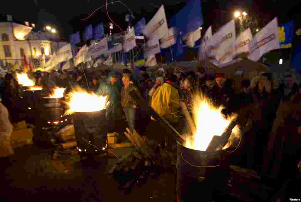 People warm themselves at fires made in steel drums after a meeting to support EU integration at European Square in Kyiv, Nov. 26, 2013.