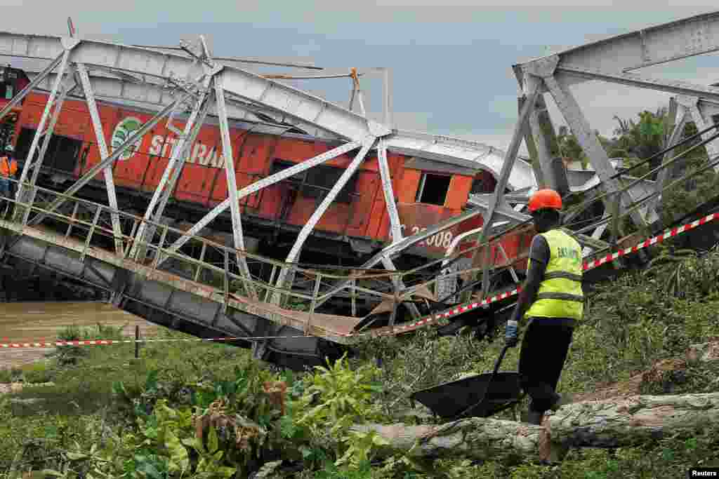 A worker walks next to a partially collapsed railroad bridge connecting Burkina Faso to Ivory Coast in Dimbokro, Ivory Coast.