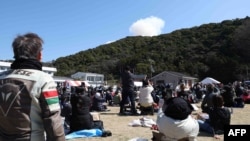 Visitors look on as smoke rises from behind a hill after a small rocket by Tokyo-based startup Space One exploded upon take-off, at the Spaceport Kili site in Kushimoto, Wakayama prefecture, on March 13, 2024.