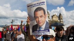 A man holds up a campaign poster of Guatemala's President Jimmy Morales during a gathering to show support for the Commissioner of the United Nations International Commission Against Impunity, Ivan Velasquez in Guatemala City, Aug. 26, 2017. 
