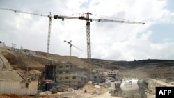 FILE - Workers and buldozers working at a construction site in the Israeli settlement of Givat Zeev near the West Bank city of Ramallah, April 14, 2016.