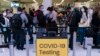 Pelancong mengantre untuk pemeriksaan di dekat tanda tempat pengujian COVID-19 di Bandara Internasional Los Angeles di Los Angeles pada 24 November 2021. (Foto: AP)