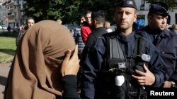 Seorang perempuan yang mengenakan jilbab dan cadar menutup matanya saat berada di dekat polisi Perancis (foto: dok). 