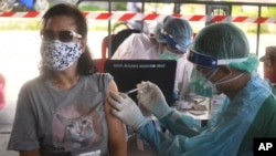 Seorang petugas kesehatan memberikan dosis vaksin AstraZeneca COVID-19 kepada warga di kawasan Klong Toey, lingkungan yang saat ini mengalami lonjakan kasus virus corona, di Bangkok, Thailand, Senin, 10 Mei 2021. (Foto: AP/Vichan Poti)