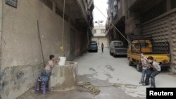 Boys use a bucket to extract water from a well in Arbeen, in the eastern Damascus suburb of Ghouta. Facing water shortages, residents started drilling wells to extract water to be used for drinking and domestic use, May 6, 2014. 