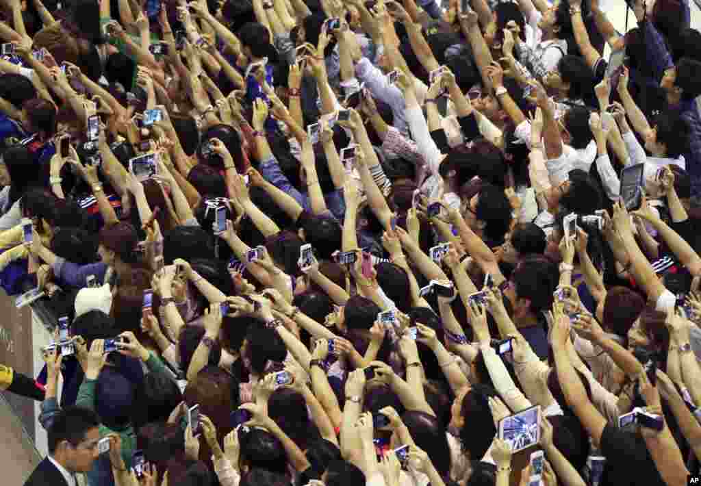 Fans of the Japanese national football (soccer) team try to take pictures of players as they return from Brazil to their home country at Narita International Airport near Tokyo.